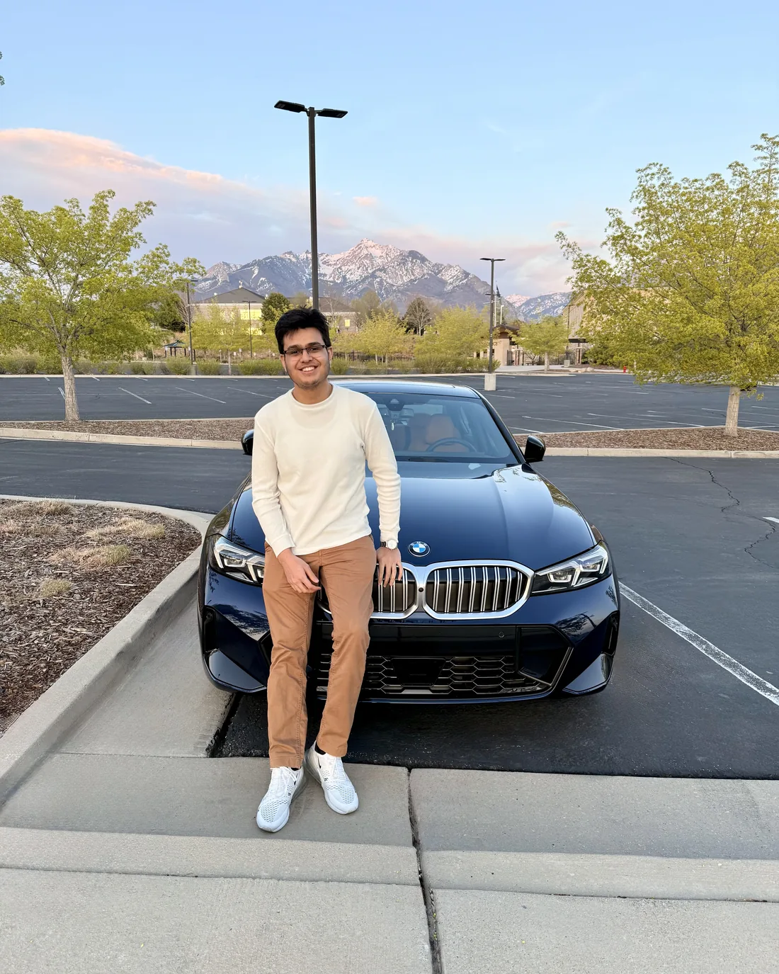 Drumin Gajjar in front of a navy BMW, snow-capped mountains in the background